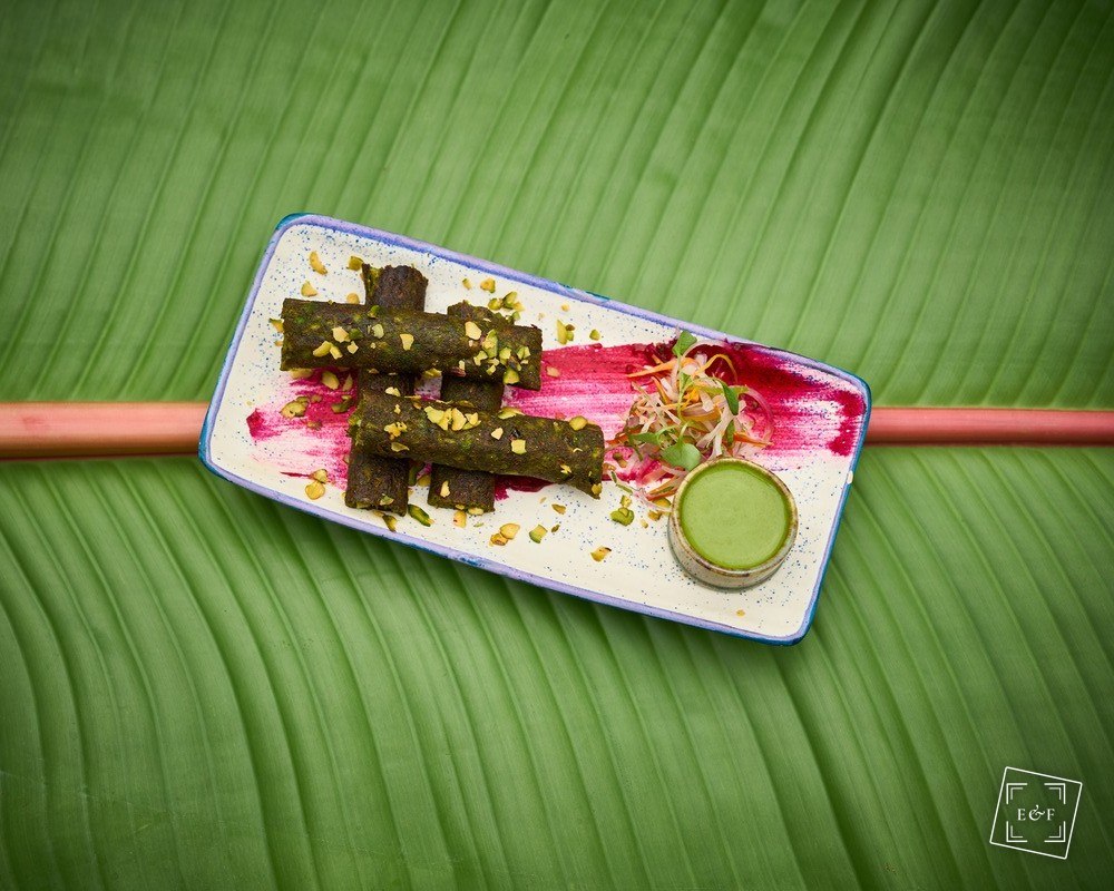 Pistachio-crusted rolls with green chutney plated on a banana leaf